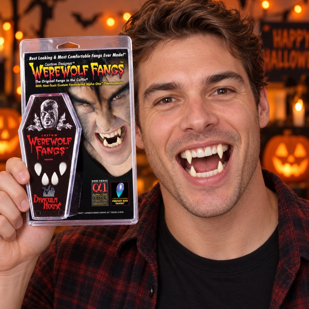 A smiling man with werewolf fangs holds up a packaged novelty product labeled 'Werewolf Fangs' in a Halloween-themed setting with warm lights and jack-o'-lanterns in the background.