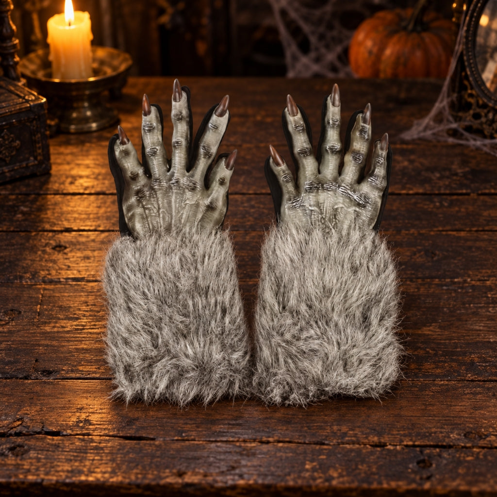 A pair of Halloween-style clawed gloves with pale gray textured hands, long dark claws, and fluffy gray faux-fur cuffs, displayed on a rustic wooden surface with candles and a pumpkin in the background.