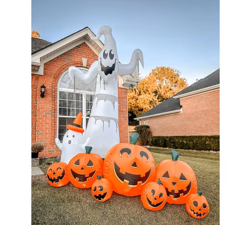 Halloween inflatable decorations including a ghost and pumpkins in front of a house.