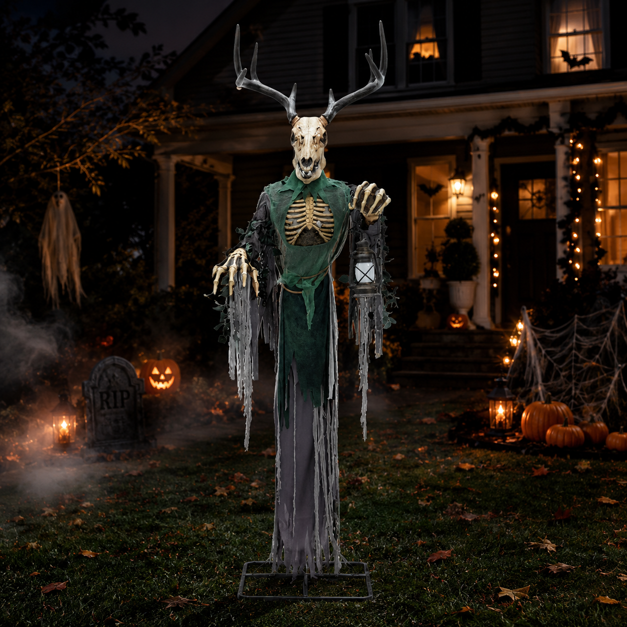 A Halloween yard decoration featuring a life-sized skeleton deer with antlers, a green tattered robe, and skeletal hands, standing on a lawn in front of a decorated house at night.