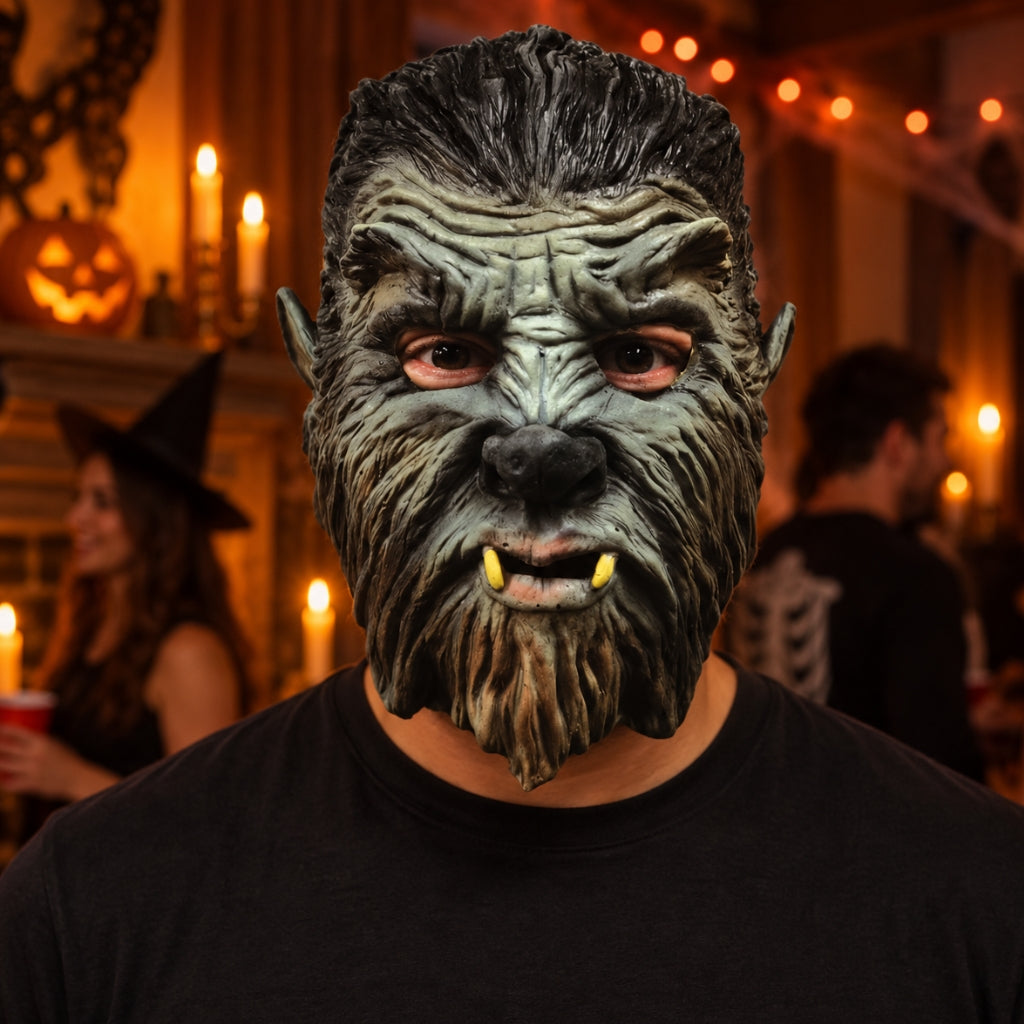 A person wearing a highly detailed werewolf mask with textured gray-green fur, yellow fangs, and pointed ears, photographed in a warmly lit Halloween party setting with candles and blurred background figures.